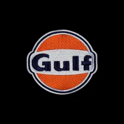 Detale haftowanego, okrągłego naszywki z logo 'Gulf' na czarnym tle, widoczna faktura materiału i precyzyjne szwy.