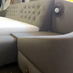 Szary narożnik z tapicerowanymi guzikami i wbudowaną lampką, z szufladą w dolnej części, wykonany w Turzy.