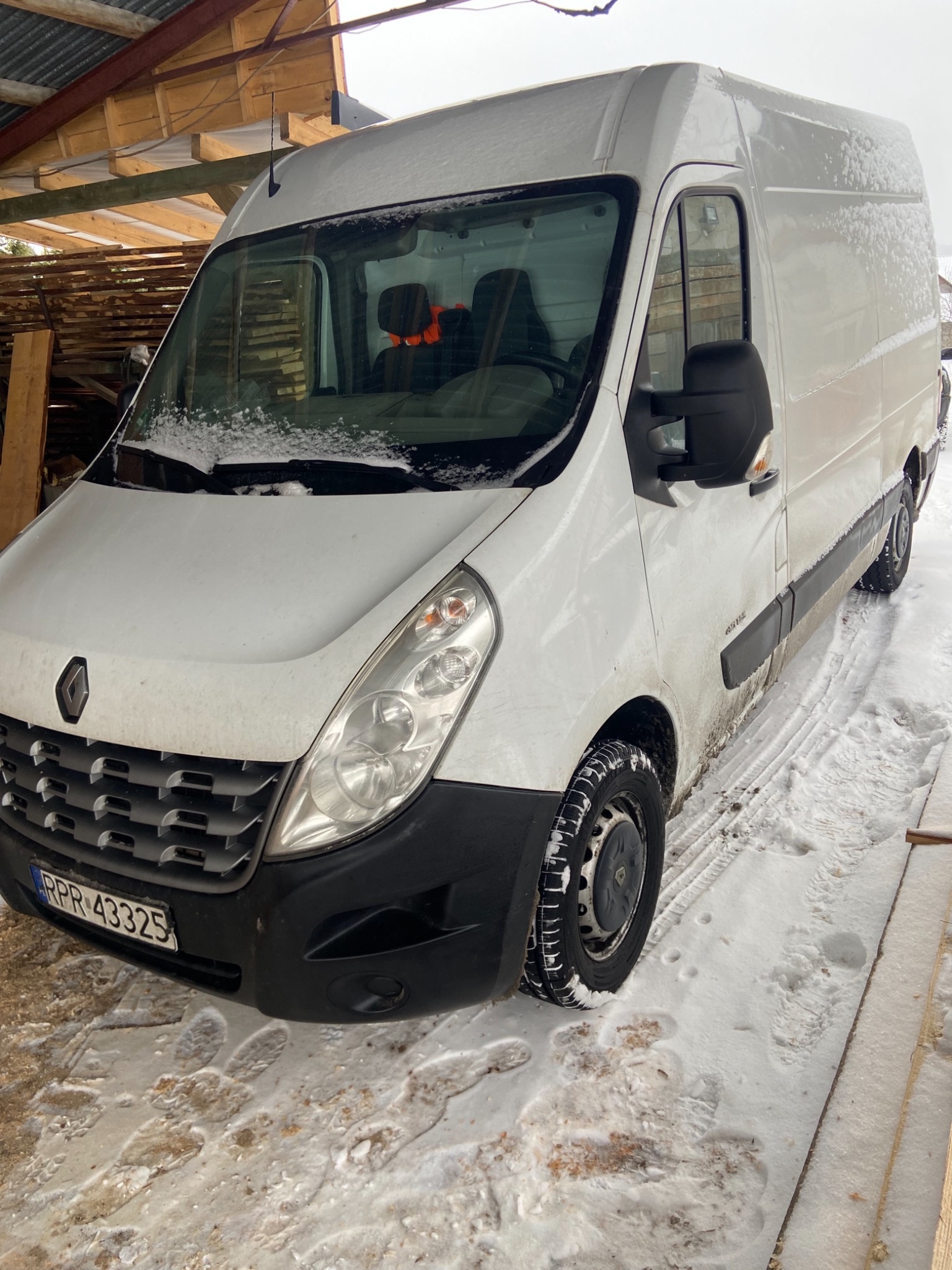 Biały samochód dostawczy Renault Master zaparkowany na śniegu z widocznymi śladami opon i tablicą rejestracyjną RPR 43325.