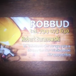Wizytówka firmy ROBBUD z numerem telefonu, imieniem i nazwiskiem Robert Baranowski, adresem w Gorzowie Wielkopolskim oraz NIP, na tle z kaskiem, młotkiem i planami.