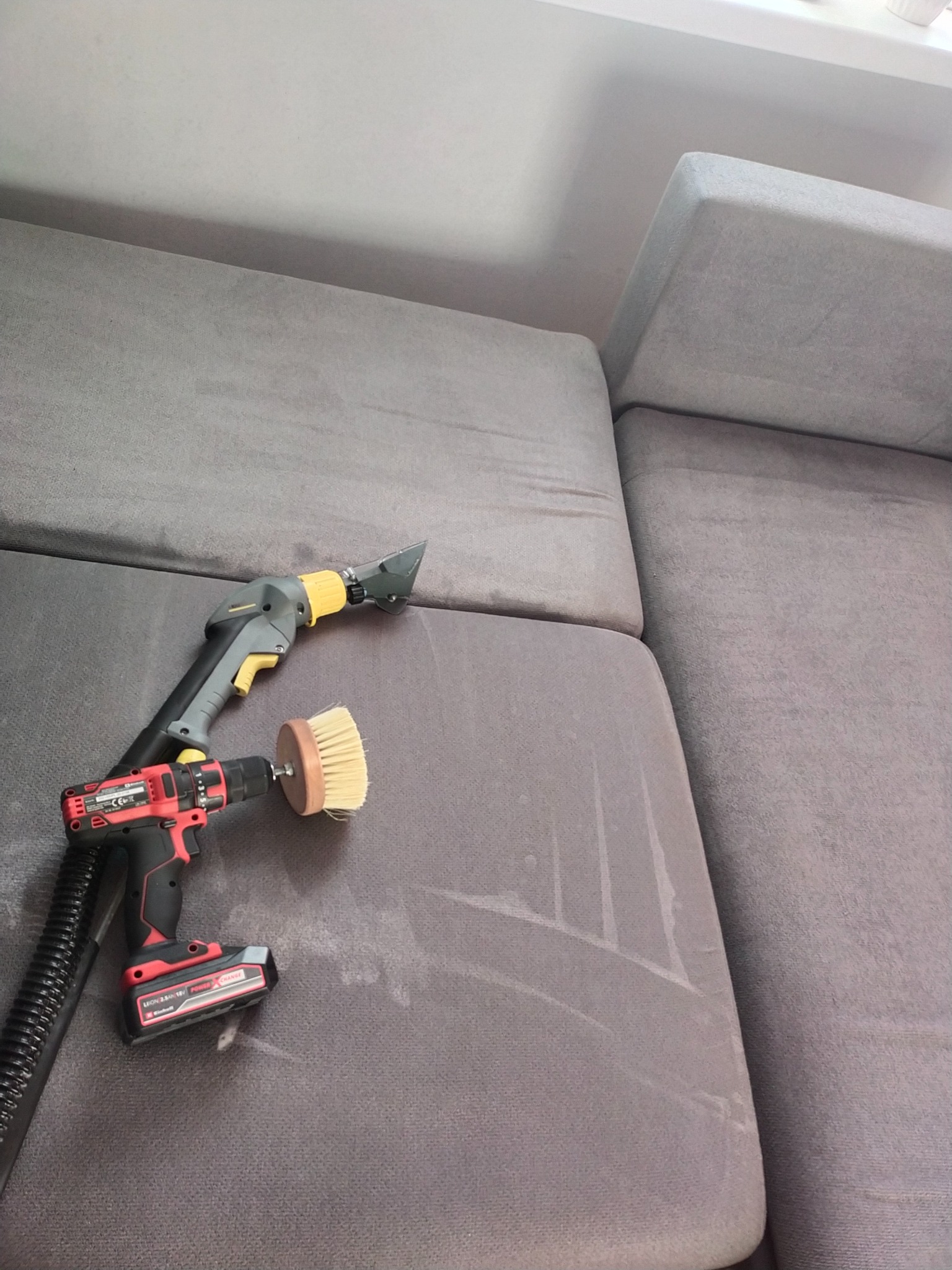 Szary narożnik w trakcie czyszczenia w Gorzkowicach, widoczne ślady po użyciu odkurzacza piorącego i szczotki na wiertarce.