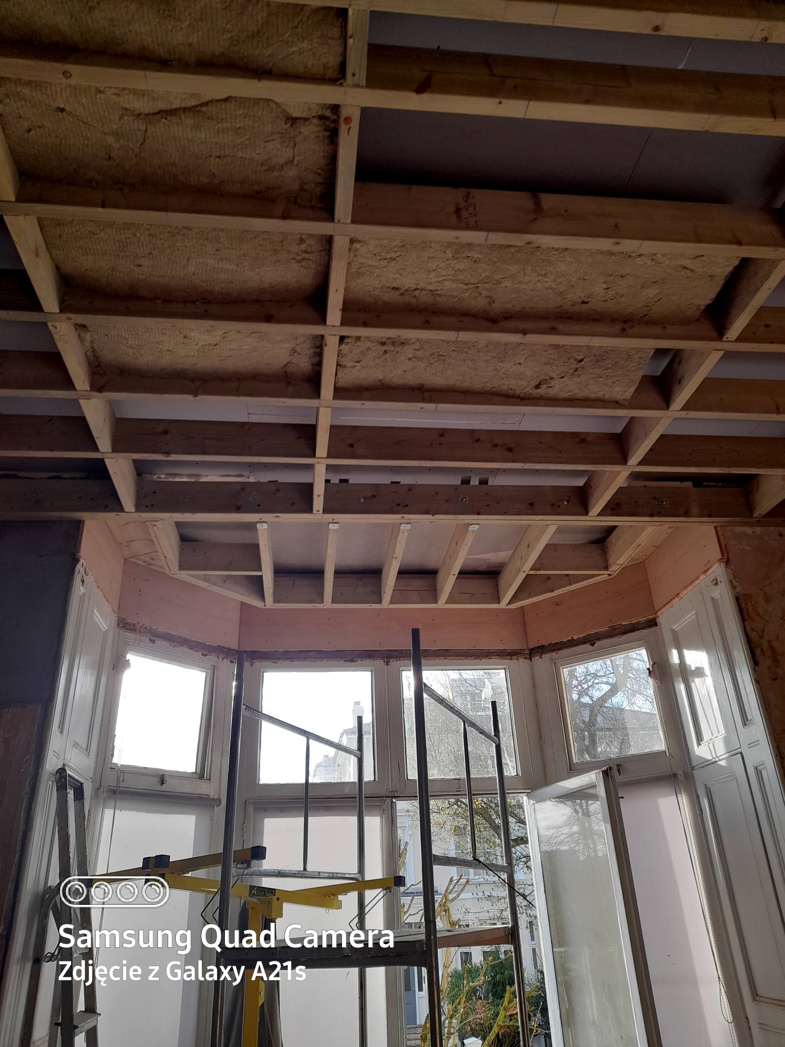 Poddasze w trakcie ocieplania wełną mineralną, widoczne drewniane legary i rusztowanie przy oknie w London.