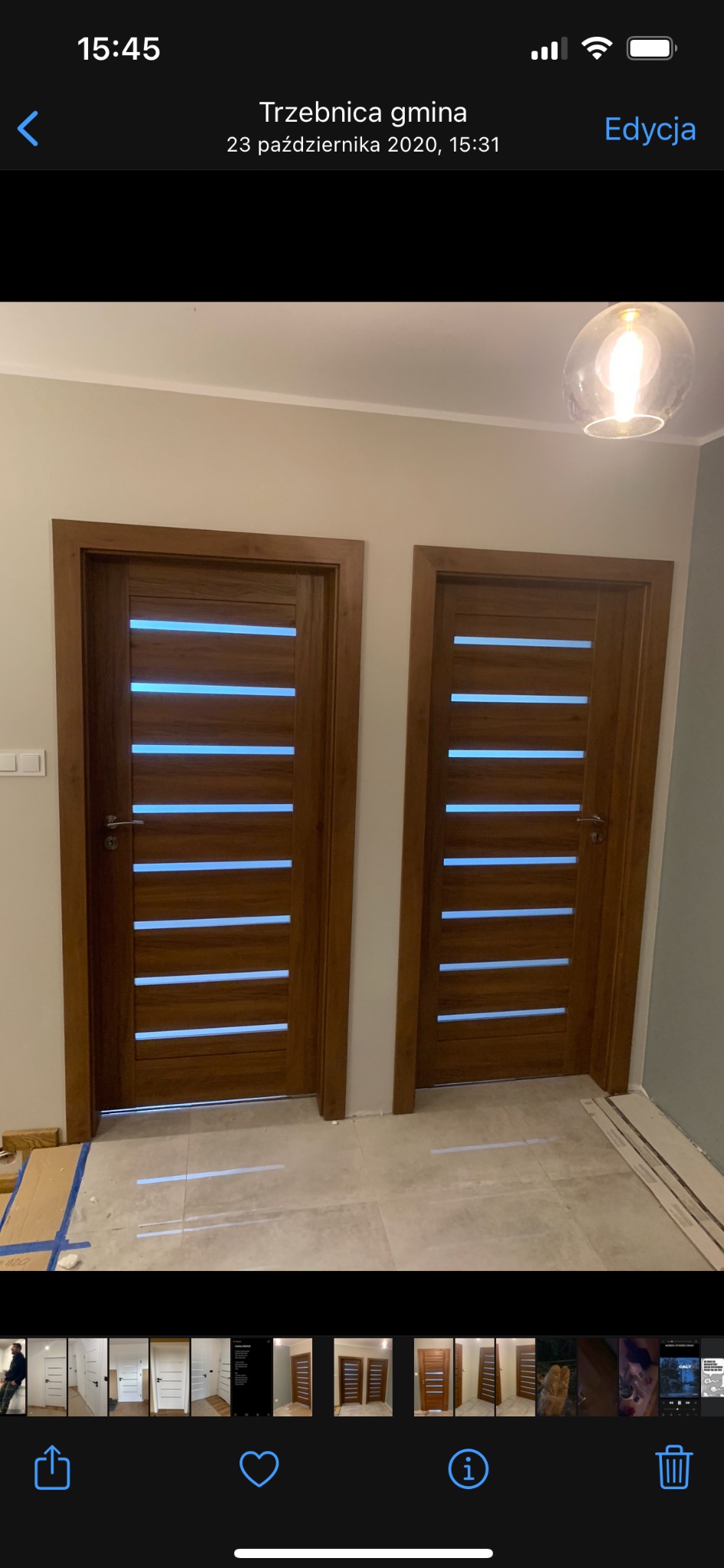 Dwa brązowe, nowoczesne drzwi wewnętrzne z poziomymi przeszkleniami, widoczne w trakcie montażu, zabezpieczone kartonem i taśmą malarską przy podłodze z szarych płytek.