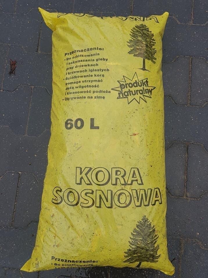 Żółty, foliowy worek 60L z korą sosnową, leżący na szarym bruku. Na worku nadrukowane informacje o przeznaczeniu produktu oraz grafika drzewa iglastego.