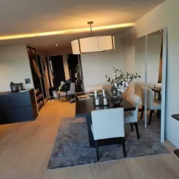 Jasne wnętrze mieszkania z drewnianą podłogą, czarnymi meblami, szarym dywanem i minimalistycznym oświetleniem sufitowym LED