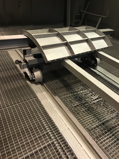 Metalowe szalunki łukowe ENCO na wózku transportowym w hali produkcyjnej, widoczne kraty podłogowe.