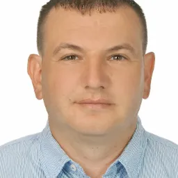 Portret mężczyzny w niebieskiej koszuli na białym tle, z widocznymi detalami twarzy i teksturą materiału koszuli.