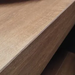 Fragment blatu z płyty laminowanej w odcieniach brązu, widoczne drobne zabrudzenia.