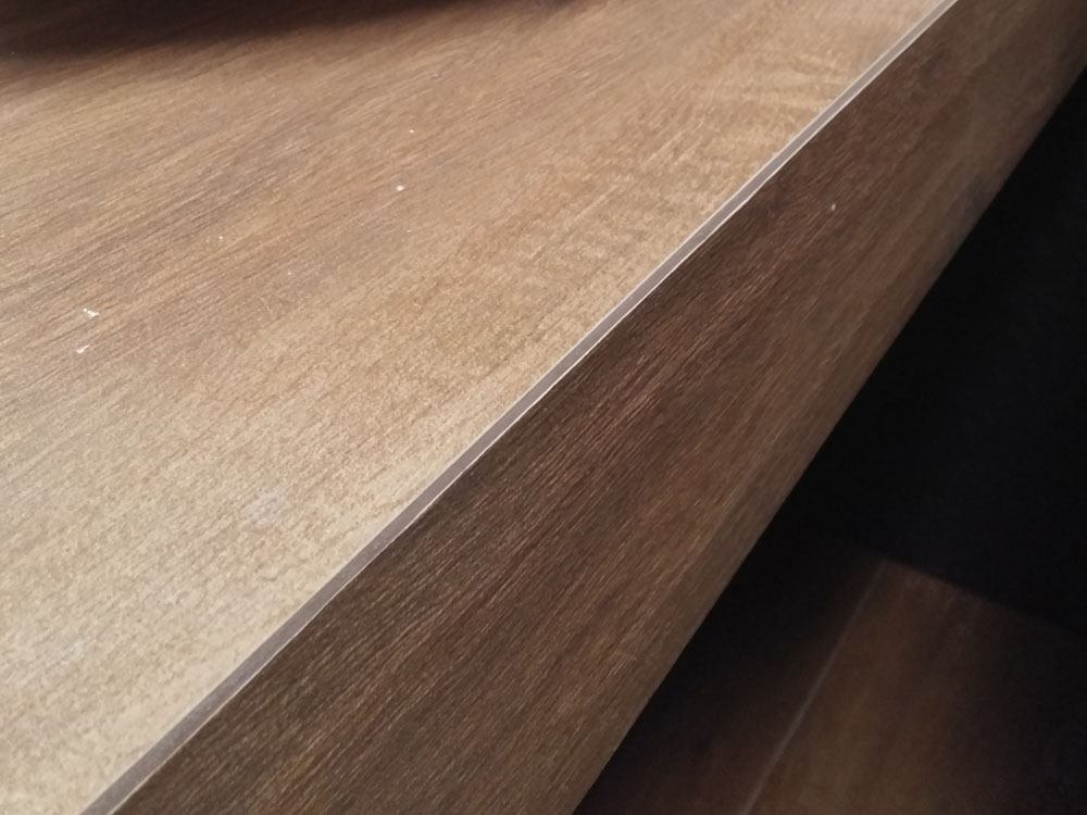 Fragment blatu z płyty laminowanej w odcieniach brązu, widoczne drobne zabrudzenia.