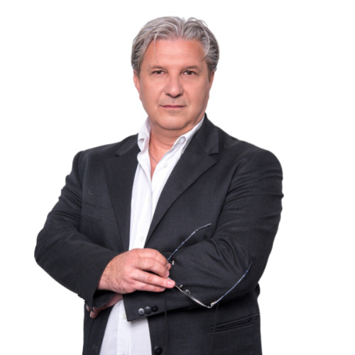 Portret biznesowy mężczyzny z siwymi włosami w czarnej marynarce, trzymającego okulary na białym tle. Profesjonalny wizerunek agenta nieruchomości.