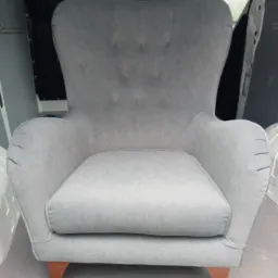 Szary fotel typu uszak z guzikami na oparciu, sfotografowany w przestrzeni ładunkowej samochodu dostawczego.