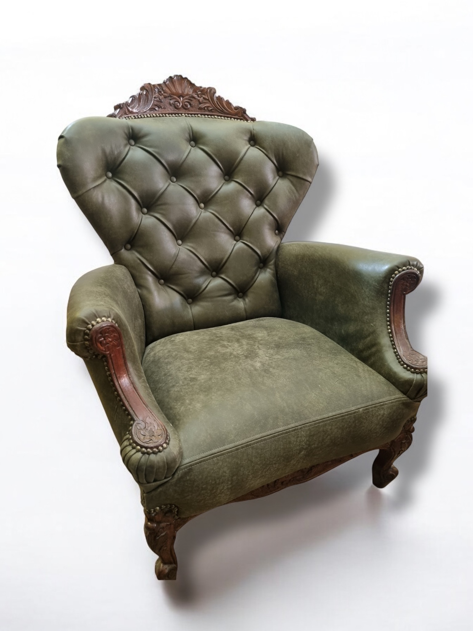 Antyczny fotel tapicerowany skórą w odcieniach zieleni, z dekoracyjnymi drewnianymi elementami, prezentowany przez firmę z Bielska-Białej.
