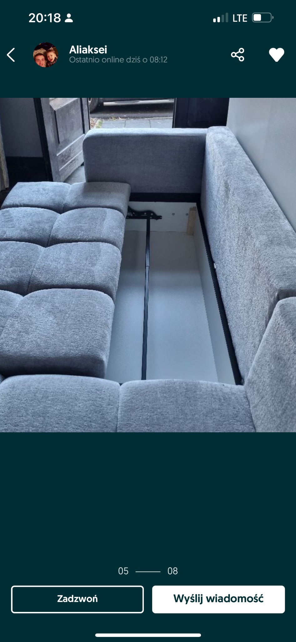 Rozkładana sofa z szarą tapicerką, widoczny mechanizm rozkładania i pojemnik na pościel.