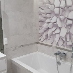 MAO Magdalena Owczarek - Nowoczesna łazienka z białą wanną obudowaną szarymi płytkami imitującymi beton, akcentująca ściana z fototapetą 3D w geometryczny wzór.