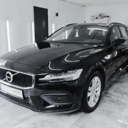 Błyszczący, czarny Volvo V60 po wizycie w myjni detailingowej, widoczne odbicia w lakierze, na podłodze czyste płytki, w tle logo S2 Detailing.