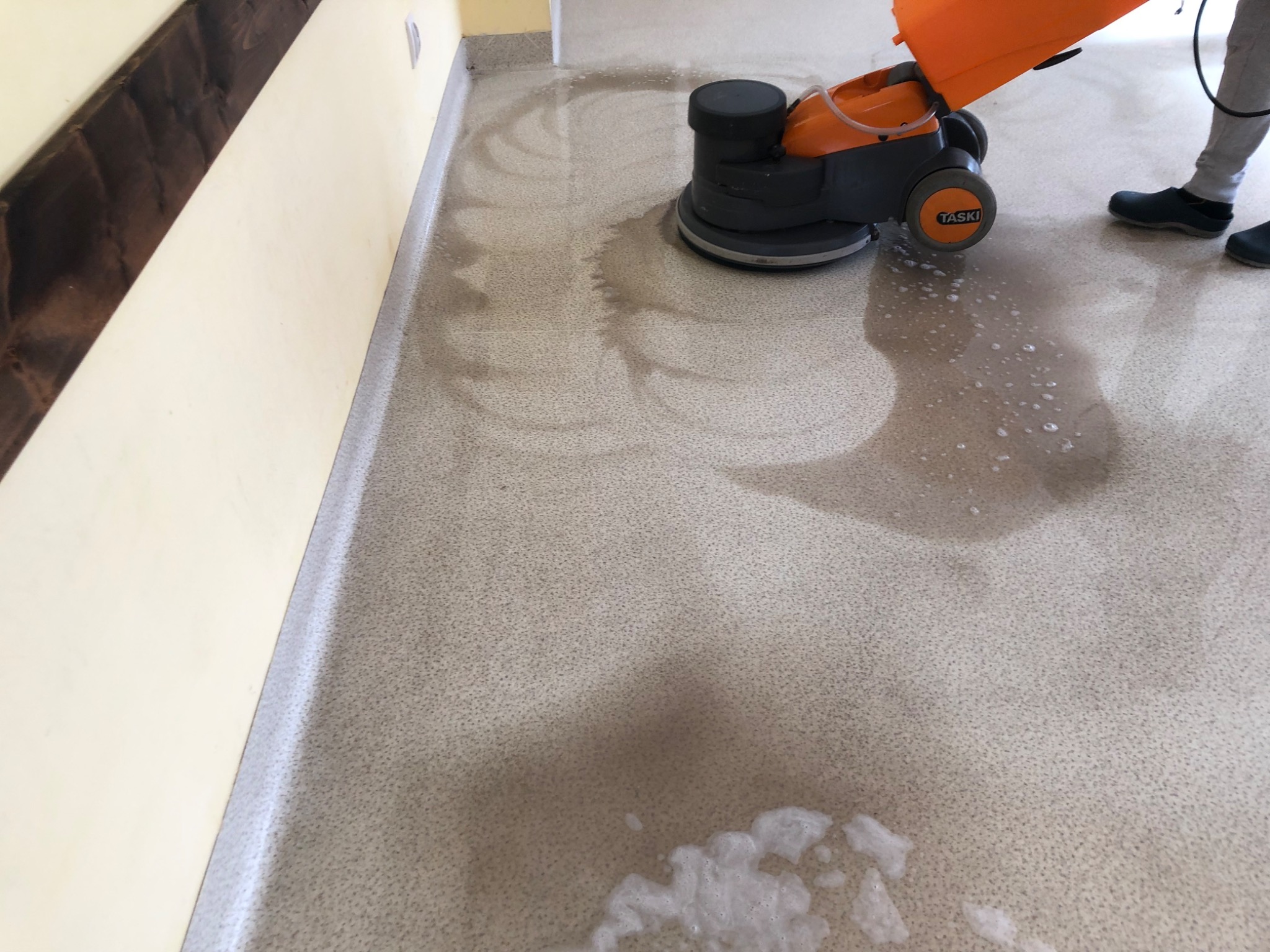 Czyszczenie podłogi z płytek za pomocą szorowarki TASKI, widoczne ślady po czyszczeniu i piana