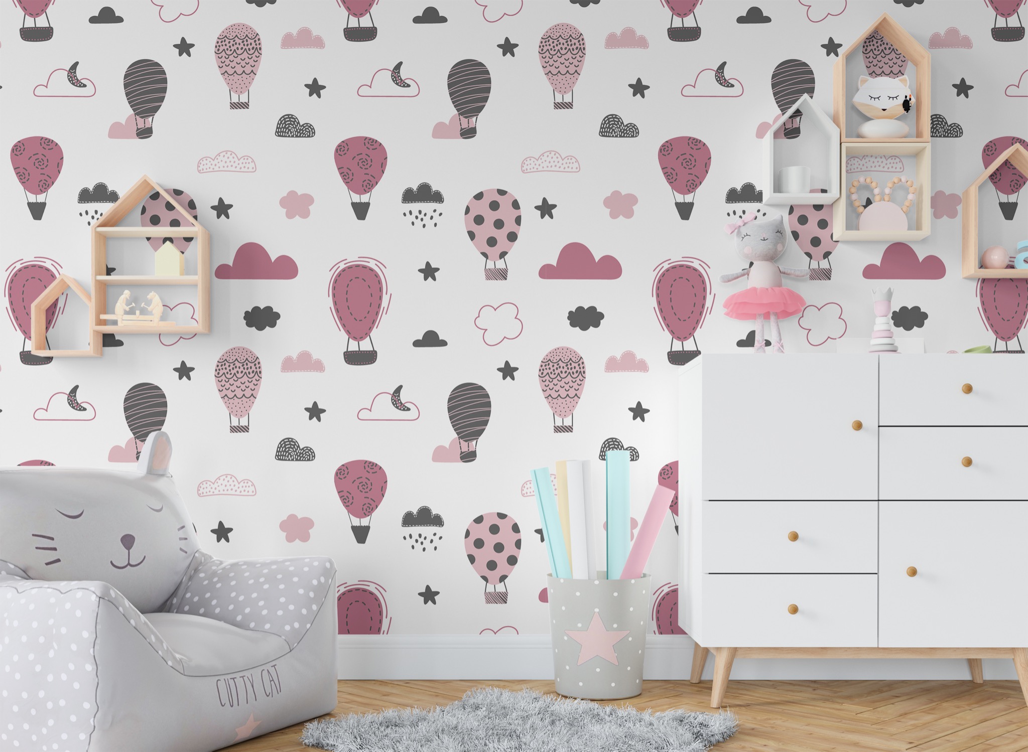 Pokój dziecięcy z tapetą w balony, fotelikiem w kształcie kota i białymi meblami.