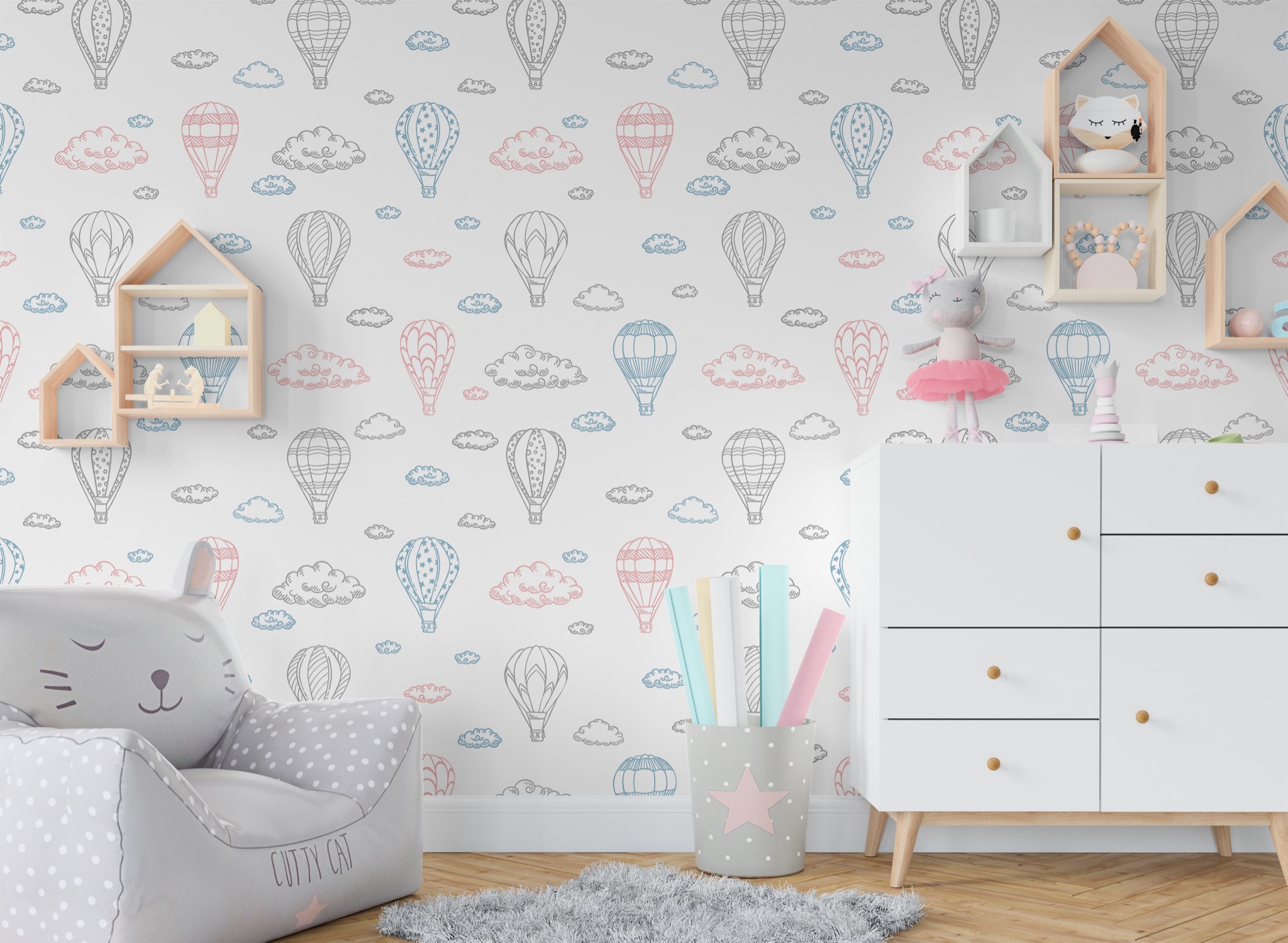 Pokój dziecięcy z tapetą w balony i chmury, białą komodą, półkami w kształcie domków, pluszowym fotelem w kształcie kota oraz dywanem.