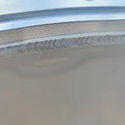 Detal metalowego elementu z widocznym spoiną po spawaniu, charakteryzującą się regularnym wzorem