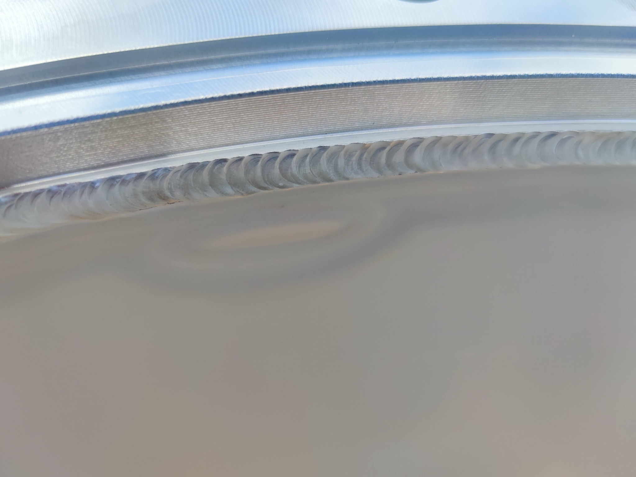 Detal metalowego elementu z widocznym spoiną po spawaniu, charakteryzującą się regularnym wzorem