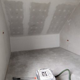 Fach-remont - Poddasze po montażu płyt gipsowo-kartonowych, widoczne łączenia szpachlowane. Na podłodze odkurzacz przemysłowy z zielonym wężem.