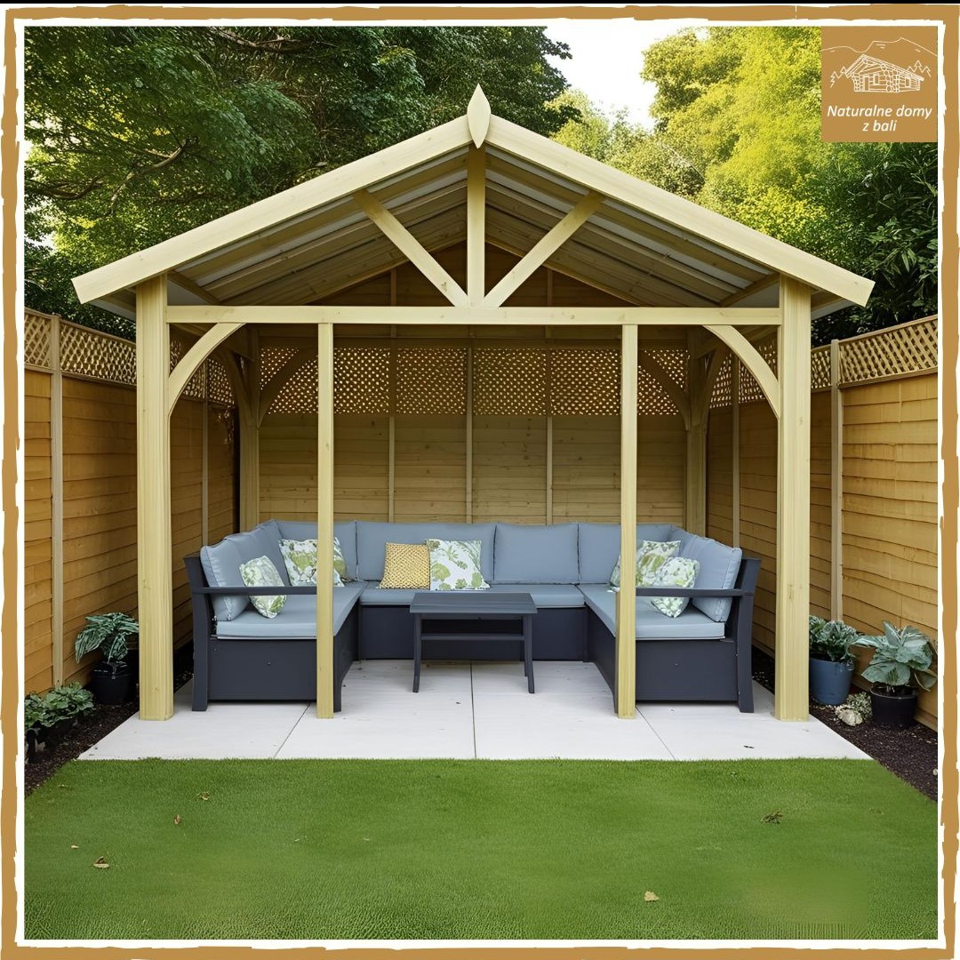 Drewniana altana ogrodowa z szarą sofą i stolikiem na betonowej płycie, otoczona zielonym trawnikiem i drewnianym płotem. Widoczne rośliny w donicach.