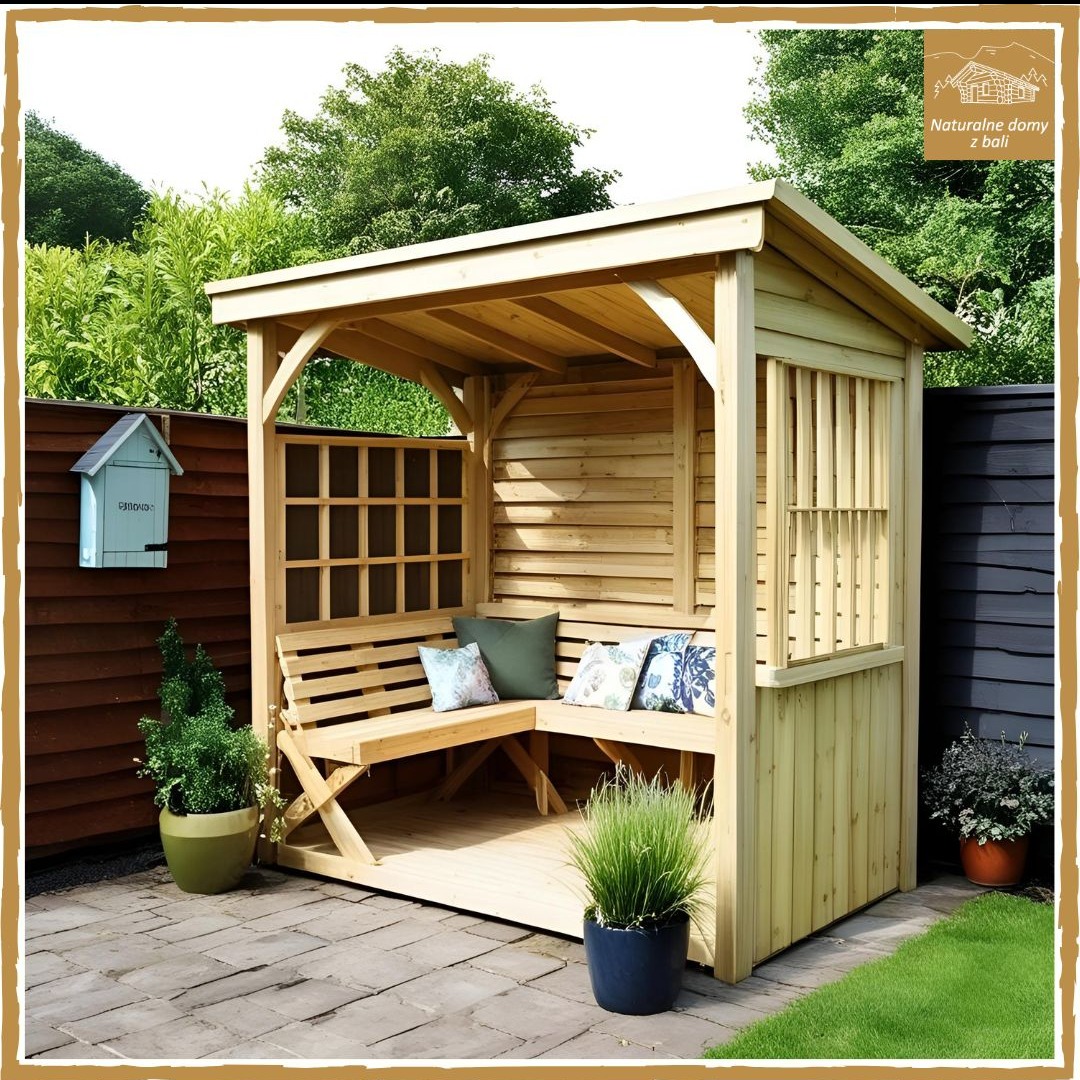 Drewniana altana z siedziskiem i poduszkami, otoczona zielenią. Na ścianie skrzynka pocztowa. Widoczna kostka brukowa i trawnik.