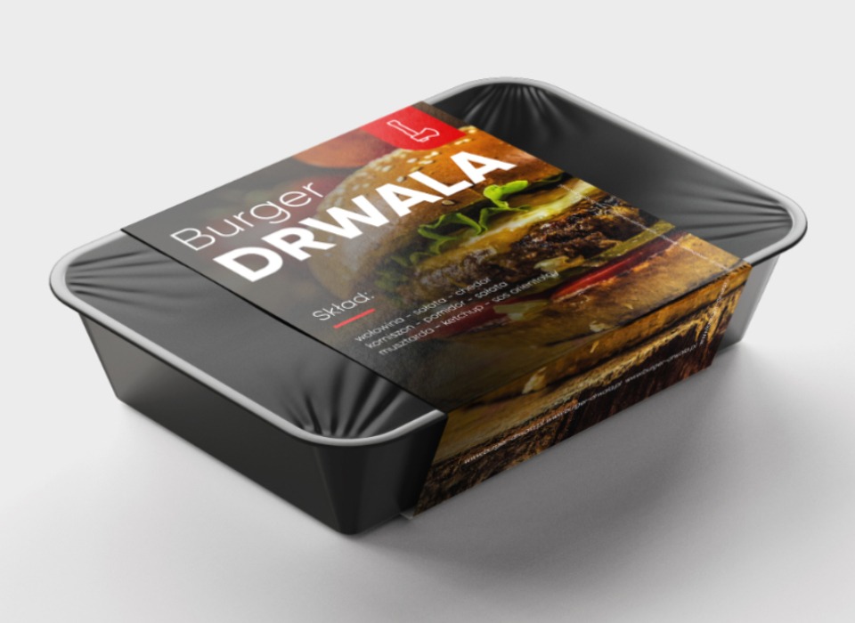 Czarny pojemnik z burgerem Drwala, owinięty folią, z etykietą prezentującą zdjęcie burgera i składniki.