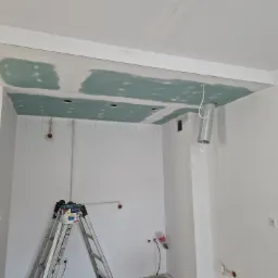 Sufit podwieszany z płyty karton gips, częściowo zaszpachlowany, widoczna drabina malarska i puszka z farbą, instalacja elektryczna.