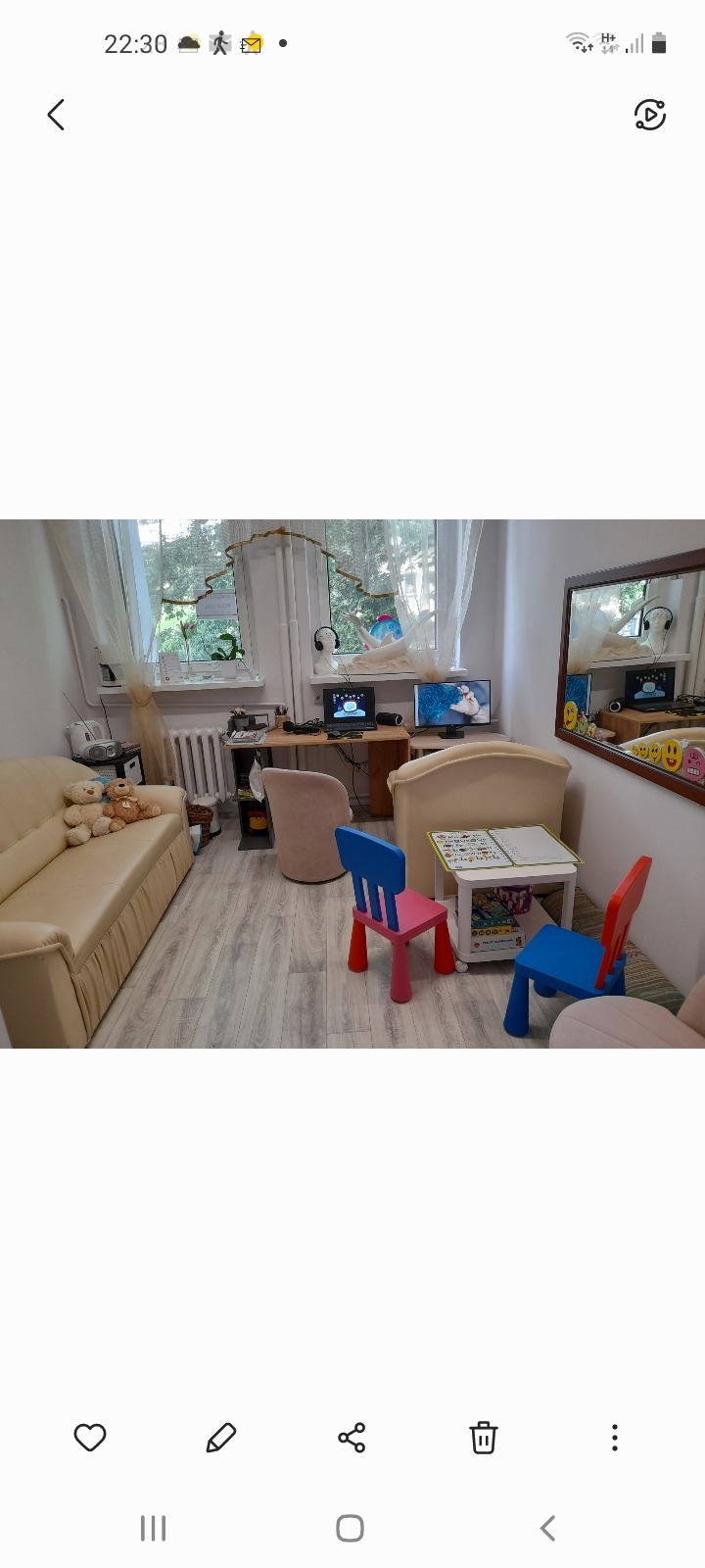 Gabinet z biurkiem, monitorem, krzesłem dla dorosłych, małą sofą z pluszakami i stolikiem z krzesełkami dla dzieci w kolorach różowym i niebieskim.