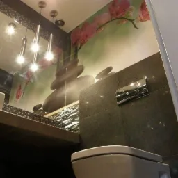 Nowoczesna łazienka z szarymi płytkami, wiszącą toaletą i fototapetą z motywem kamieni zen i kwiatów orchidei, oświetlona trzema wiszącymi lampami tubowymi.