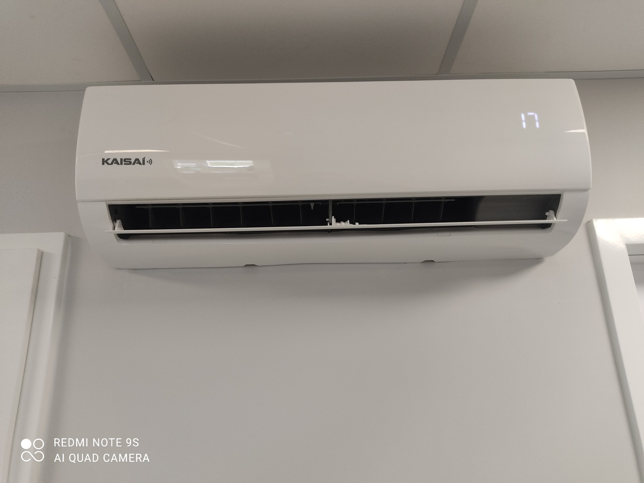 Biały klimatyzator Kaisai zamontowany na jasnej ścianie, wyświetlający temperaturę 17 stopni Celsjusza.