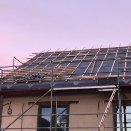 Express Dekarskie - Budowa dachu z widoczną membraną, łatami i częściowo ułożoną dachówką, uchwycone o zmierzchu z rusztowania.