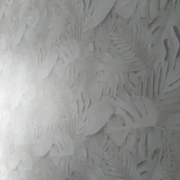 Ściana pokryta tapetą z tłoczonym wzorem liści monstery i palm w odcieniach bieli i beżu, z delikatnym cieniowaniem podkreślającym trójwymiarowość wzoru.