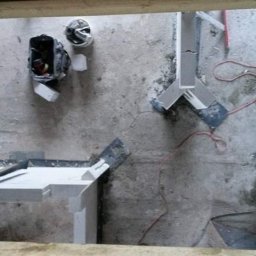 Lux-bud - Widok z góry na surowy betonowy sufit z elementami konstrukcyjnymi z profili, narzędziami i torbą narzędziową, sugerujący prace wykończeniowe w trakcie realizacji.