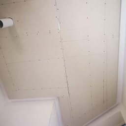 Lux-bud - Sufit z zamontowanymi płytami gipsowo-kartonowymi, widoczne łączenia i wkręty, fragment instalacji wentylacyjnej w rogu.