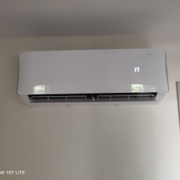 HYDROINSTAL-OZE Sławomir Łętocha - Biała klimatyzacja na ścianie, widoczny wyświetlacz z temperaturą 17 stopni, obok framuga drzwi. Minimalistyczny design, neutralne tło.