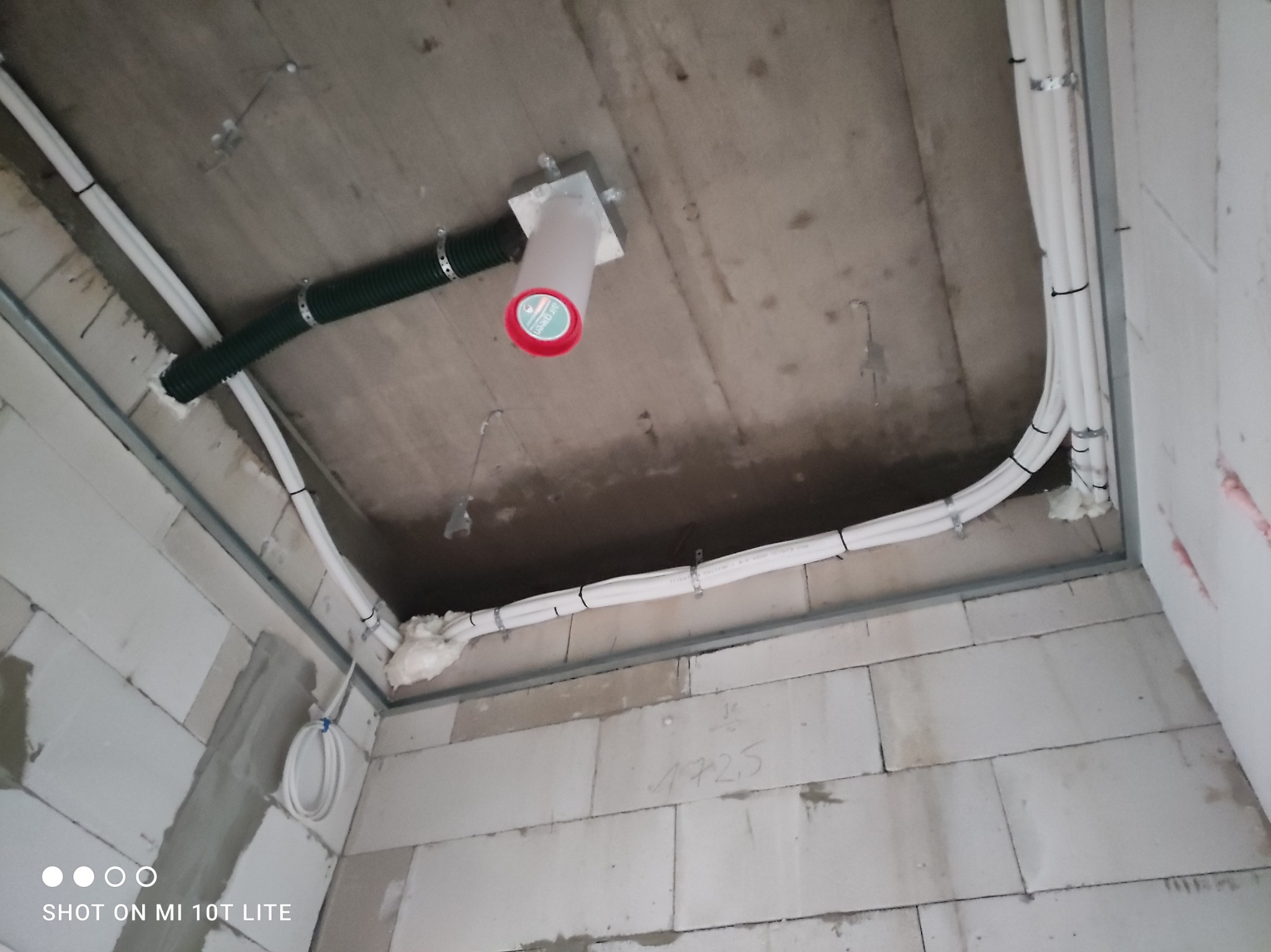 Instalacja rur wentylacyjnych i białych rur w nowym budynku z betonu komórkowego, widok z dołu. Rury przymocowane do sufitu i ścian za pomocą uchwytów.