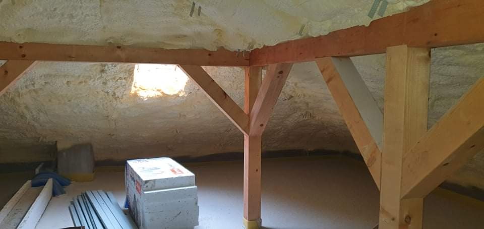 Poddasze ocieplone pianą PUR z widoczną drewnianą konstrukcją więźby i materiałami budowlanymi na podłodze.