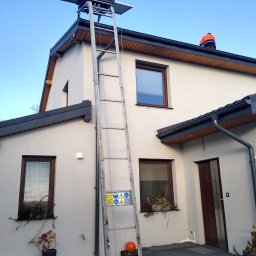 NLOOK SPÓŁKA Z OGRANICZONĄ ODPOWIEDZIALNOŚCIĄ - Montaż paneli słonecznych na dachu domu jednorodzinnego przy użyciu windy dekarskiej, widoczny pracownik w pomarańczowej kamizelce na dachu.