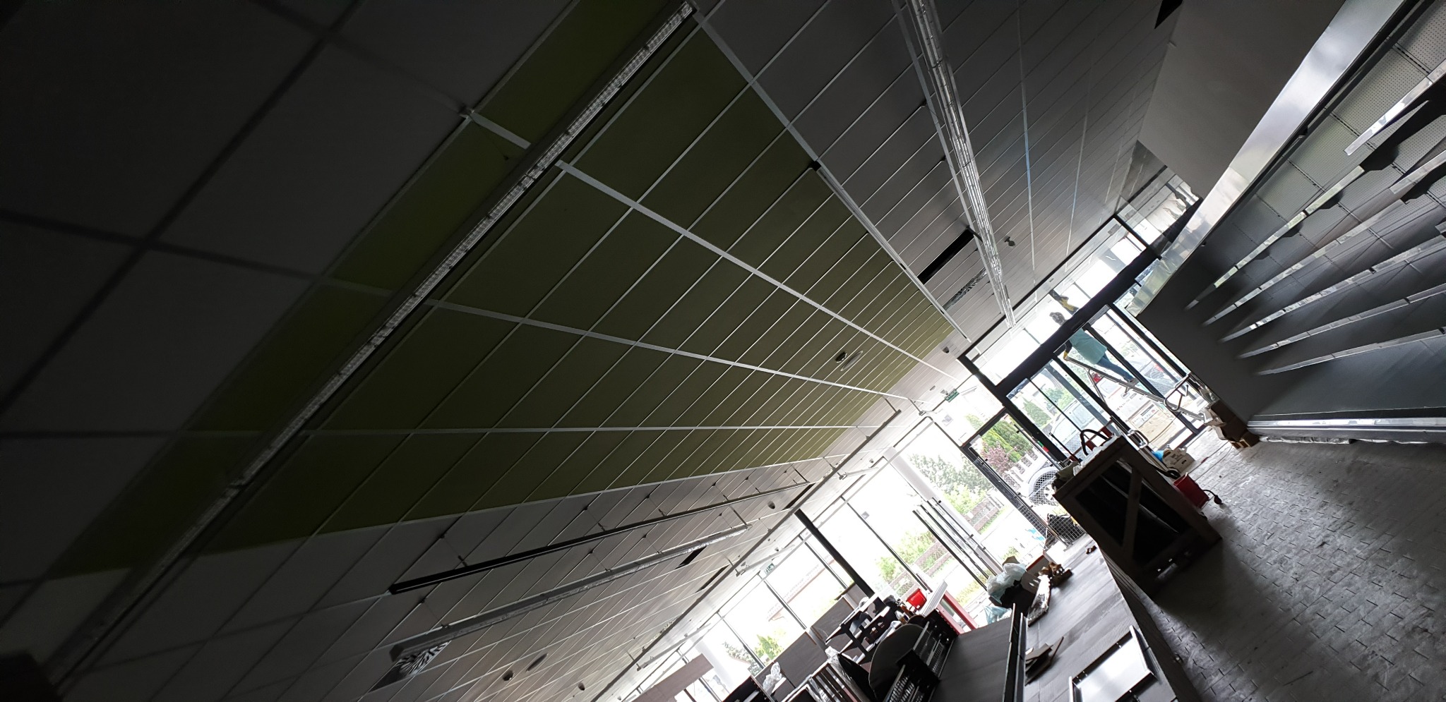 Montaż sufitu podwieszanego z płyt karton gips, widoczne profile i płyty, częściowo zamontowane oświetlenie, pomieszczenie w trakcie wykańczania.