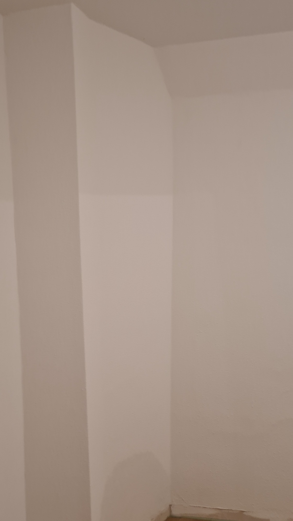 Pomieszczenie po malowaniu ścian na jednolity, jasny odcień, widoczne narożniki i przypodłogowe listwy.