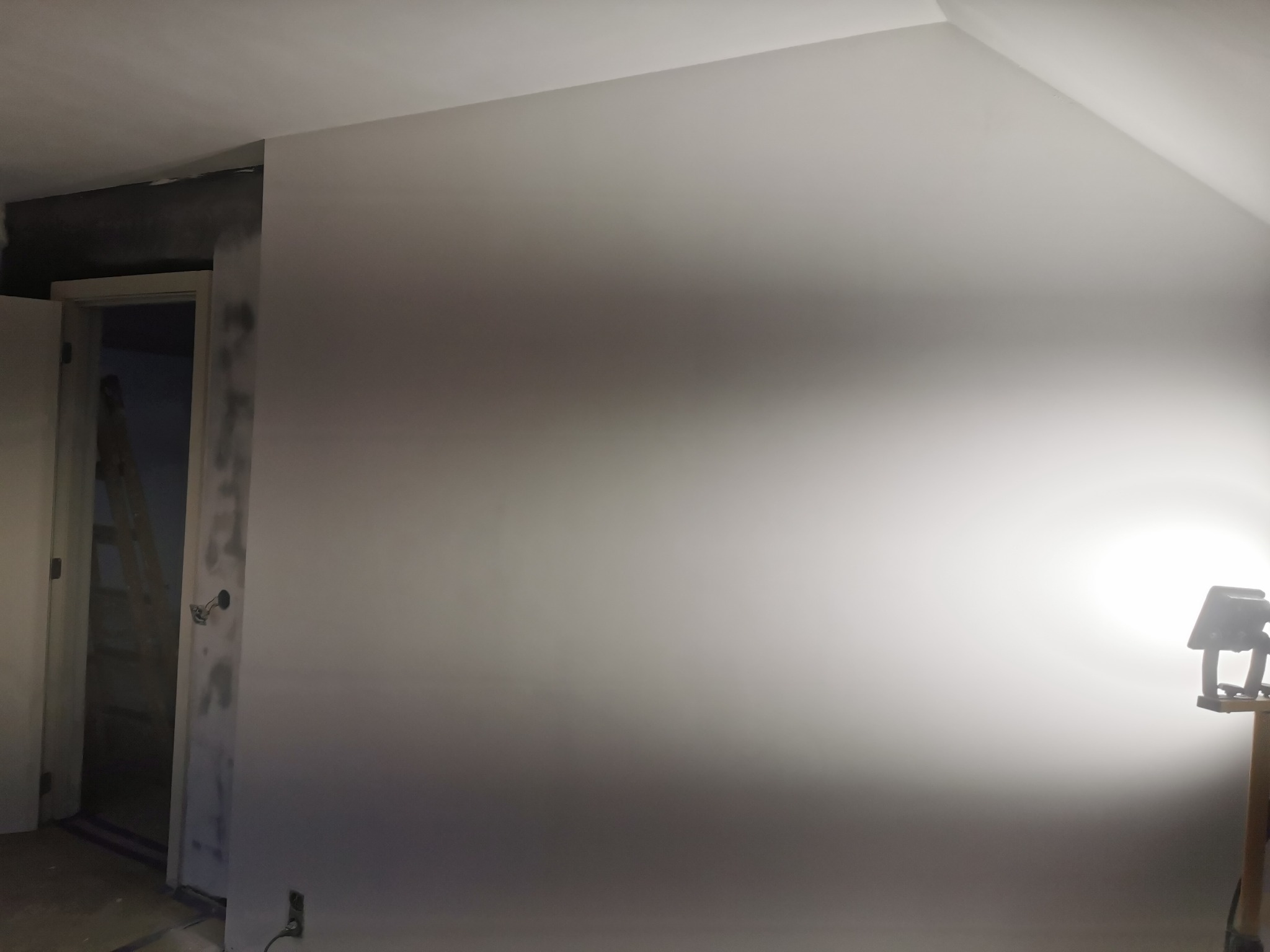 Świeżo wyszpachlowana ściana w trakcie prac wykończeniowych w Nowym Sączu, widoczne niedoskonałości i lampa doświetlająca.