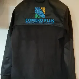 Czarna kurtka softshell z wyhaftowanym logo firmy Comeko Plus, specjalizującej się w systemach fotowoltaicznych, widok z tyłu.
