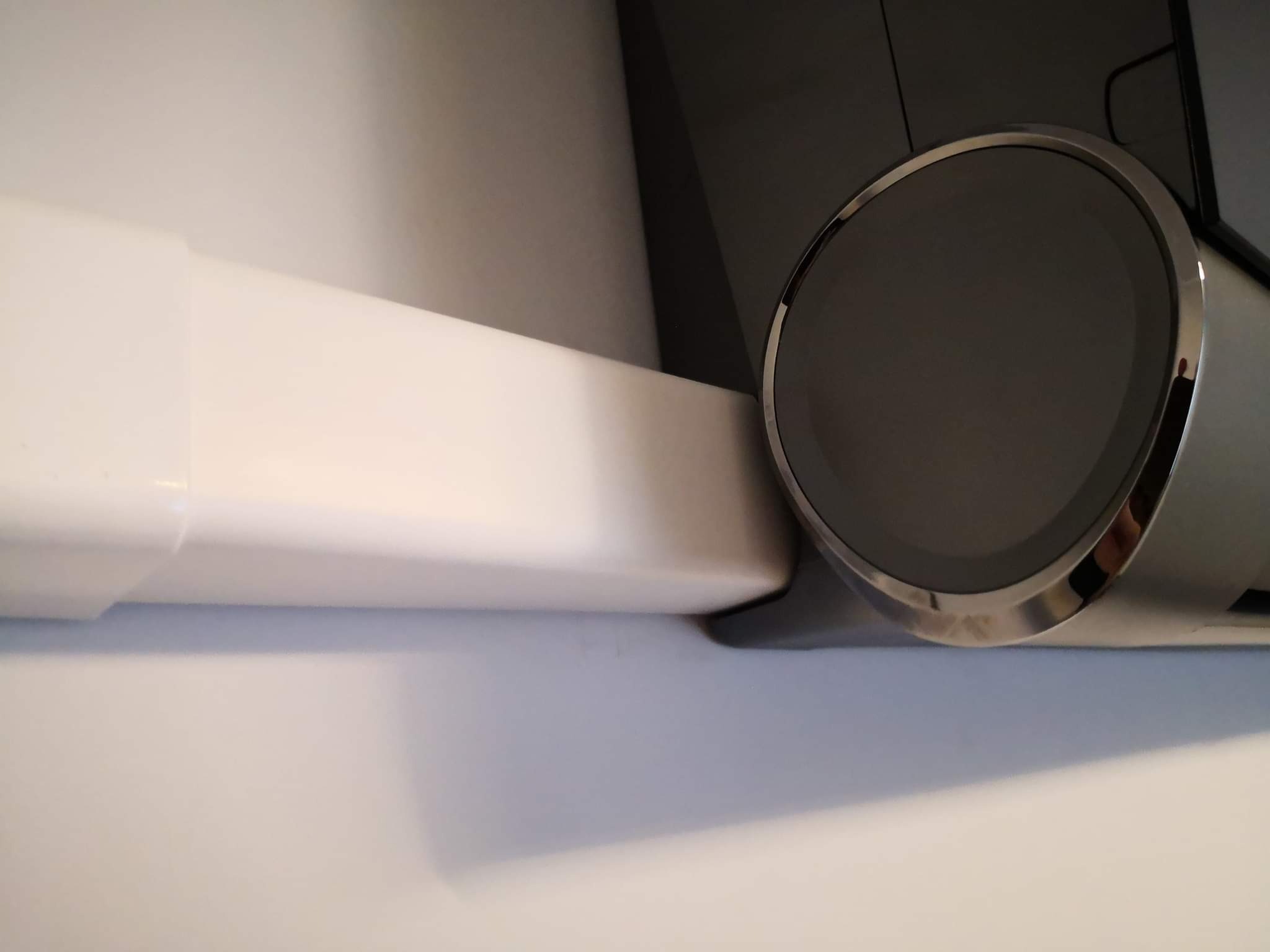 Wnętrze z widocznym fragmentem nowoczesnego klimatyzatora ściennego w kolorze białym i srebrnym, zamontowanego tuż przy suficie.