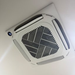 Thermopol - Biały, kasetonowy klimatyzator sufitowy marki Rotenso, z widocznym cyfrowym wyświetlaczem temperatury '22', estetycznie wkomponowany w biały sufit.