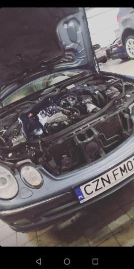 Otwarta maska niebieskiego samochodu, widoczny silnik i tablica rejestracyjna CZN FM01.