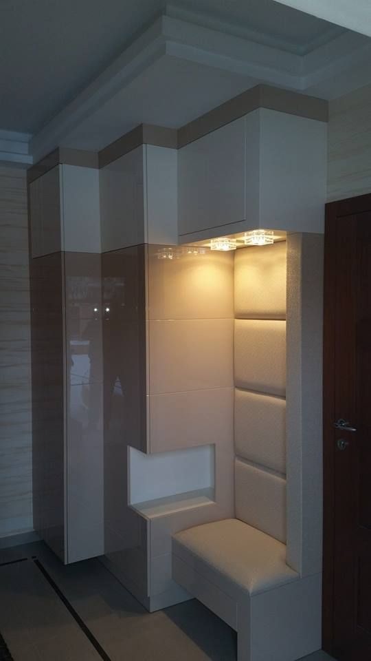 Zabudowa przedpokoju z szafą z połyskiem, tapicerowanym siedziskiem i oświetleniem punktowym, w kolorach beżu i bieli.