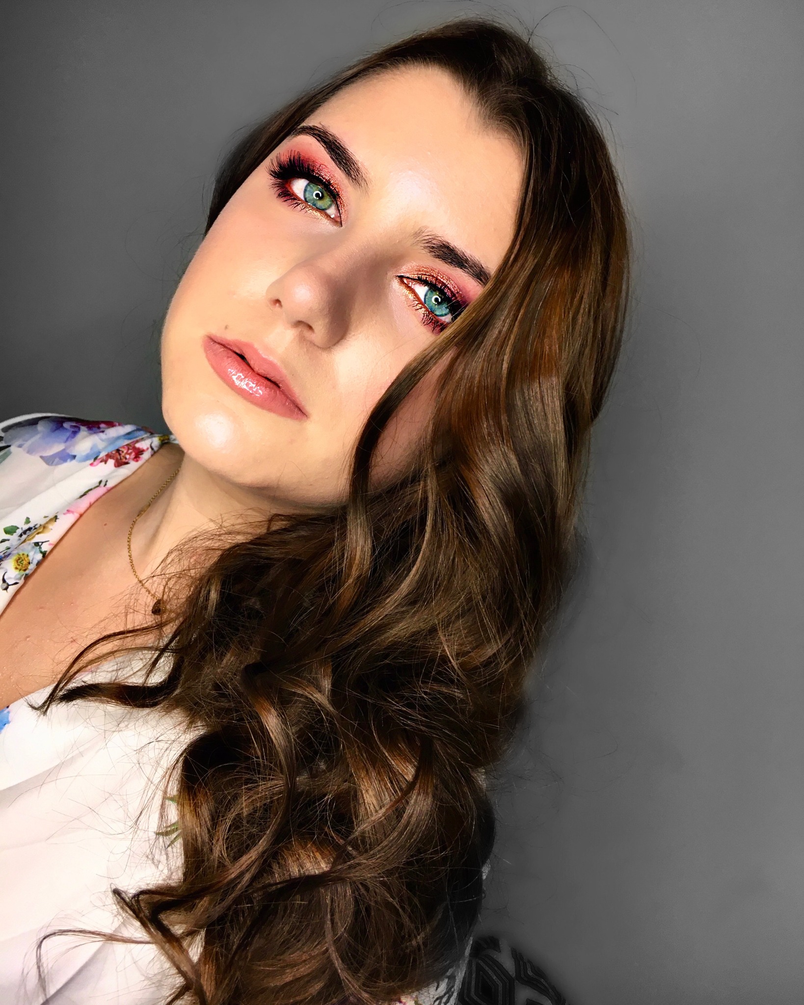 Portret kobiety z intensywnym, różowo-złotym makijażem oczu i błyszczącymi ustami w Krakowie, prezentujący efektowny wygląd.