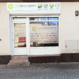 Fasada biura Superubezpieczenia.pl z widocznym logo i numerem telefonu na witrynie, ułożona kostka brukowa przed wejściem.